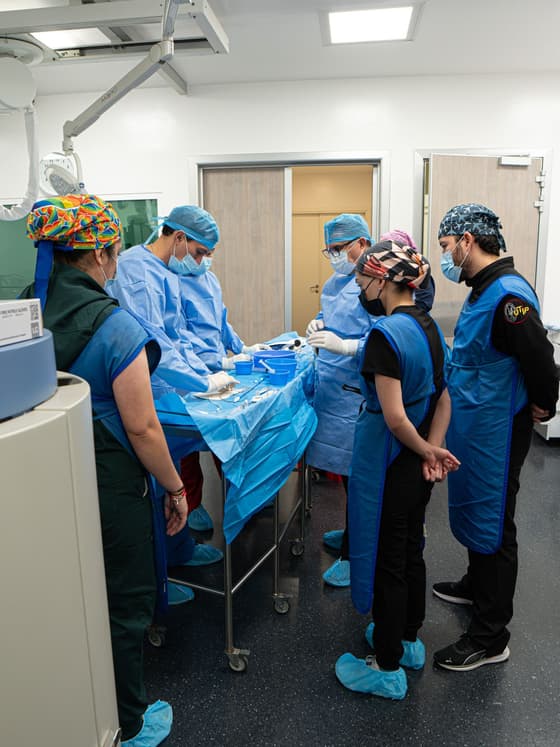Equipo médico completo trabajando alrededor de la mesa quirúrgica en un procedimiento pediátrico.