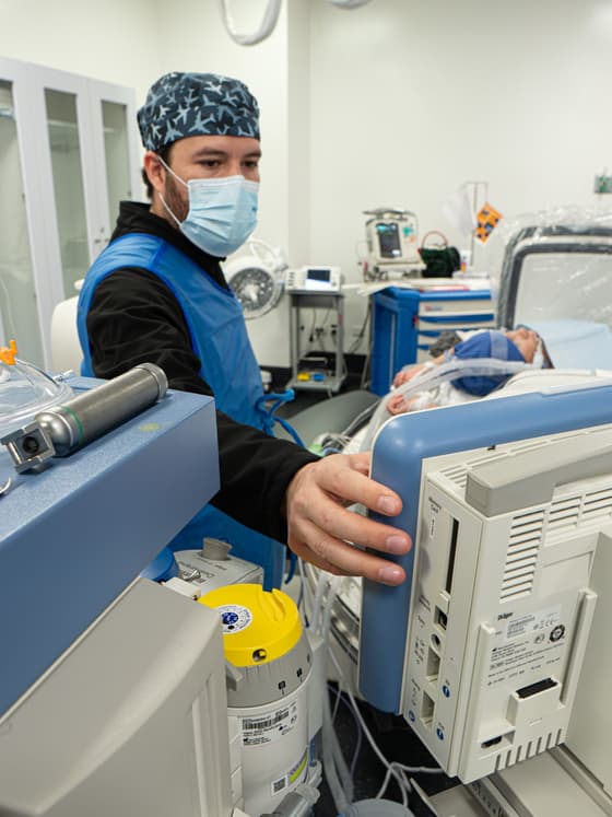 El Dr. Ramsés Zúñiga ajustando el monitor de signos vitales junto a la cama de un paciente pediátrico.