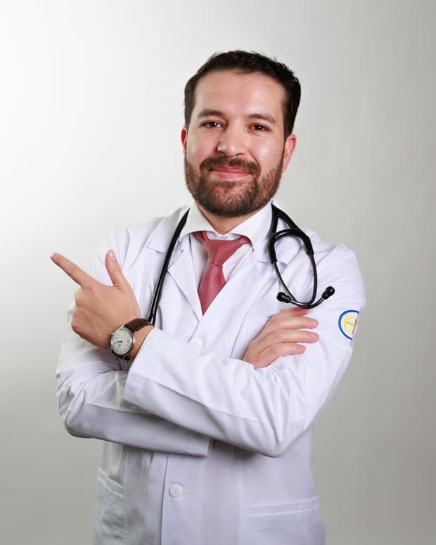 El Dr. Ramsés Zúñiga en bata blanca con estetoscopio, señalando hacia un lado.
