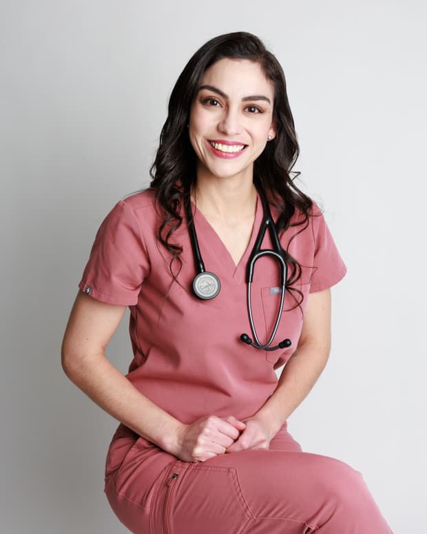 La Dra. Mariana Macías sonriendo, sentada en uniforme quirúrgico con su estetoscopio.