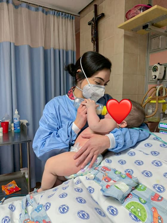 La Dra. Mariana Macías cargando a un bebé en la cama de hospital durante su recuperación.