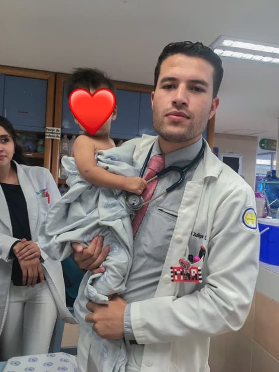 El Dr. Ramsés Zúñiga cargando en brazos a una paciente pequeña en el área de hospitalización.